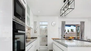 Una cocina moderna con armarios blancos, horno de acero inoxidable y una isla grande con fregadero.