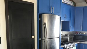 Eine Küche mit blauen Schränken, einem Edelstahl-Kühlschrank, einem Herd und einer Mikrowelle.