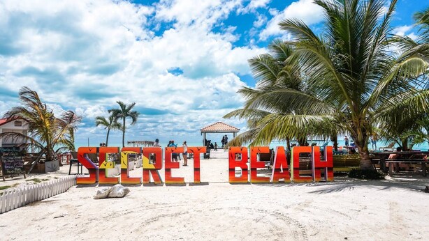 Ein Strand mit einem Schild, auf dem 'SECRET BEACH' steht.