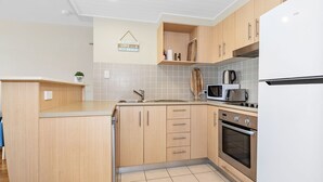 A modern kitchen with wooden cabinets, a stainless steel sink, a microwave, and an oven. - Resort on the Beach 5114 15 with resort Pool (Kingscliff)