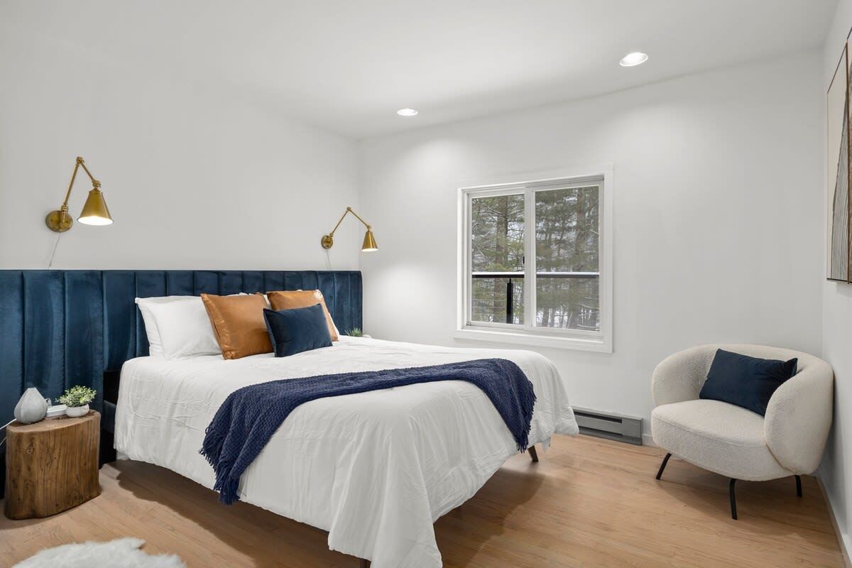 Une chambre à coucher avec un lit, des lampes de chevet, une chaise et une fenêtre.