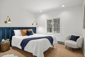 Une chambre à coucher avec un lit, des lampes de chevet, une chaise et une fenêtre.