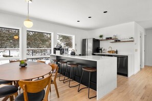 Une cuisine moderne dotée d’un îlot central, de tabourets de bar et d’une table à manger.