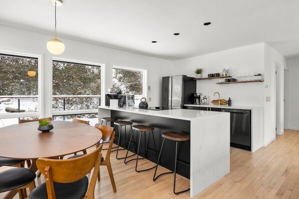 Una cocina moderna con una isla central, taburetes de bar y una mesa de comedor.