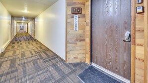 Een hotelgang met een tapijtvloer, een welkomstbord en een houten deur met een codeerapparaat.