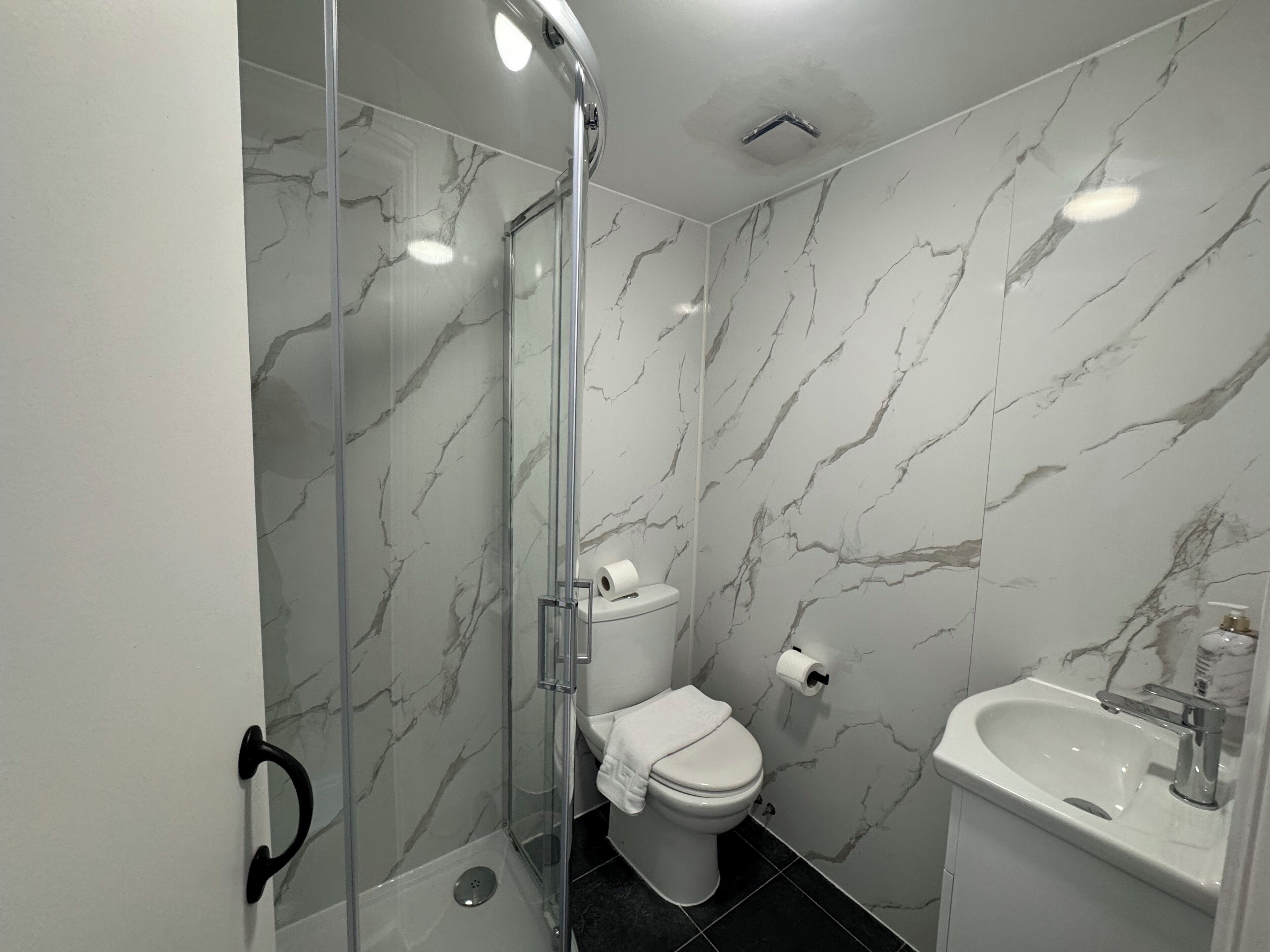 Une salle de bain avec une douche à parois de verre, des toilettes et un lavabo.