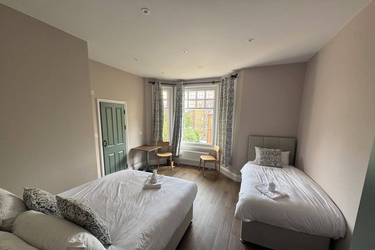 A bedroom with two beds, a desk, and a chair.