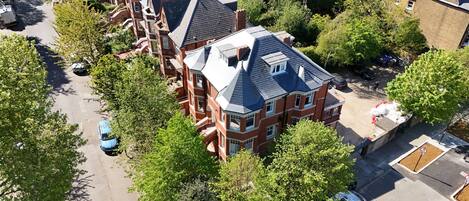 A residential area with a prominent red brick house featuring a gabled roof and multiple windows.