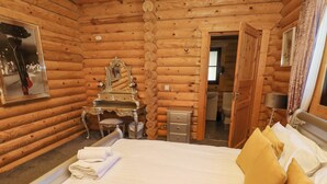 Camera da letto in tipico stile baita, con un letto, una toeletta con specchio e un bagno piccolo visibile attraverso una porta aperta.