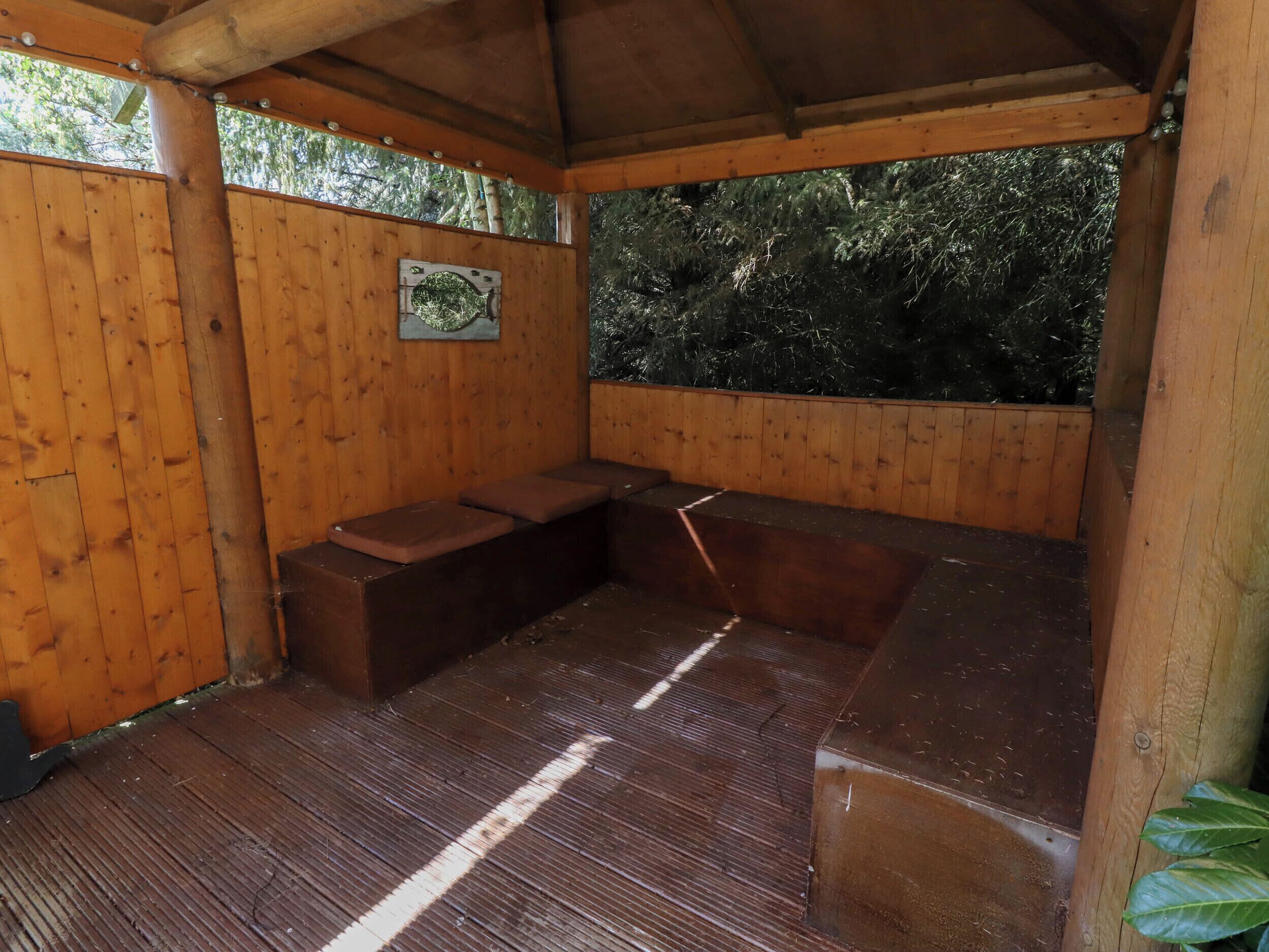 A wooden outdoor seating area with benches and a wooden floor.