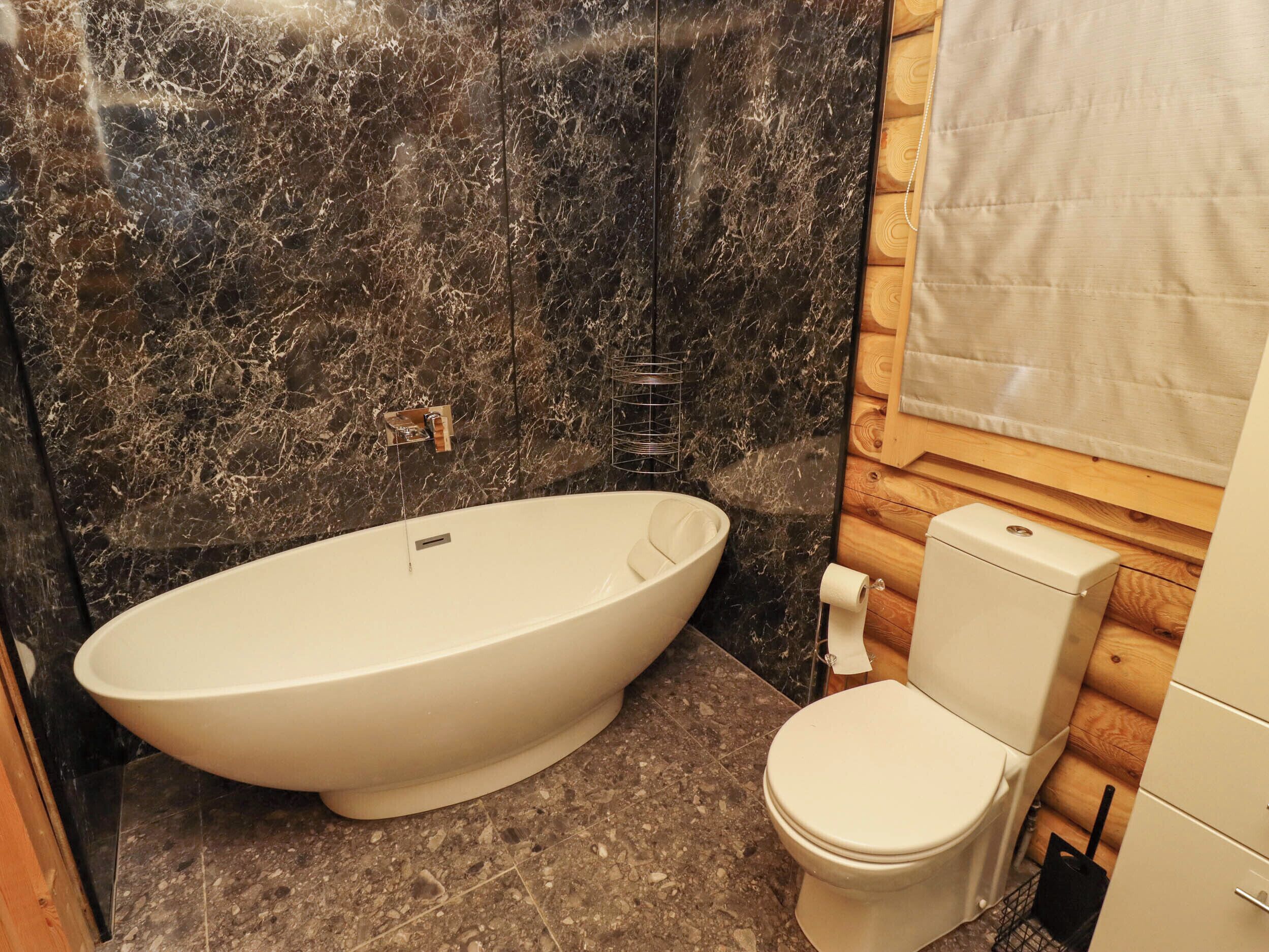 A bathroom with a freestanding bathtub, a toilet, and a towel rack.