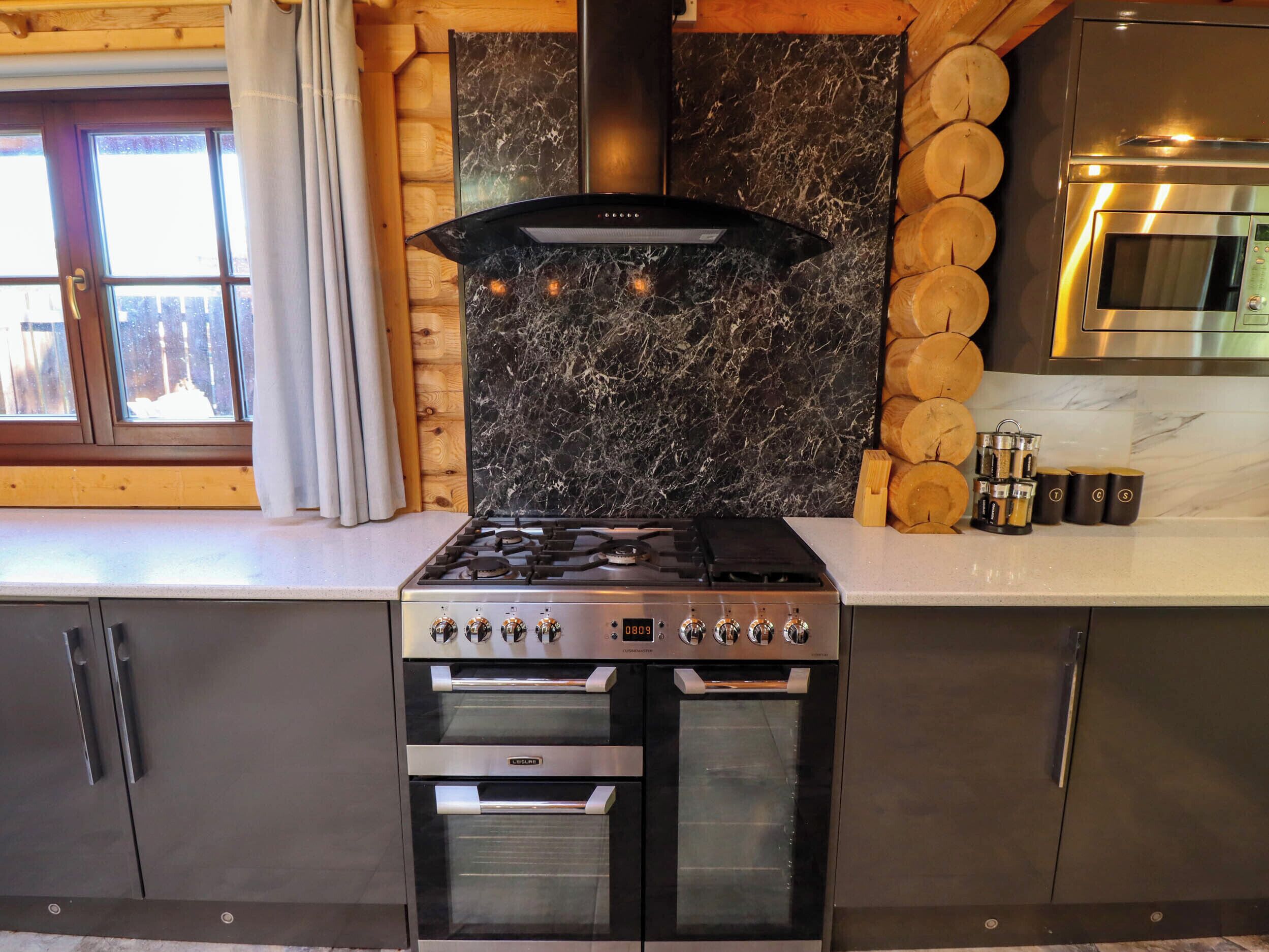 Cocina con estufa a gas, horno y campana extractora moderna.