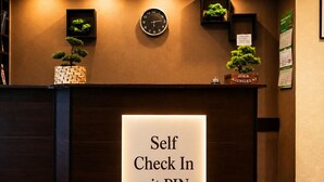 Una taquilla de recepció amb un senyal que diu 'Self Check In mit PIN' i un rellotge a sobre.