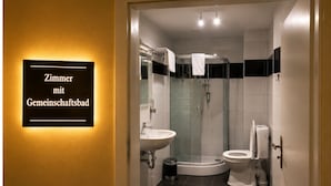 Un bany modern amb dutxa de vidre, un vàter separat i un lavabo.