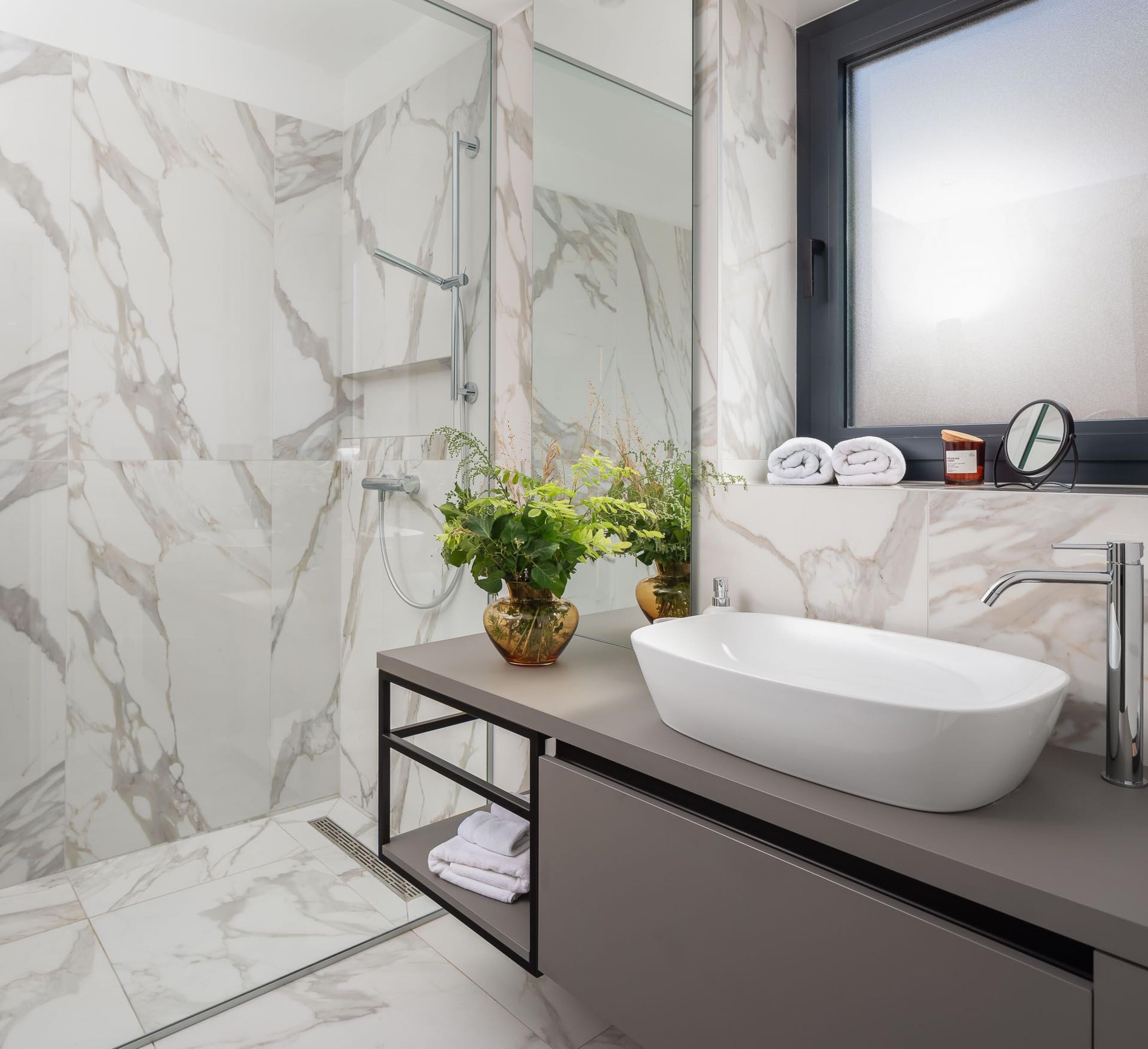 Un baño moderno con un lavamanos grande de color blanco, una cabina de ducha de vidrio y un salpicadero de mármol.
