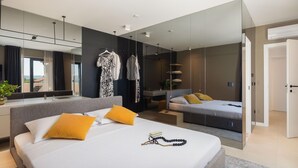 Moderni hotellihuone, jossa on suuri sänky, yöpöytä, peili ja vaatekaappi.