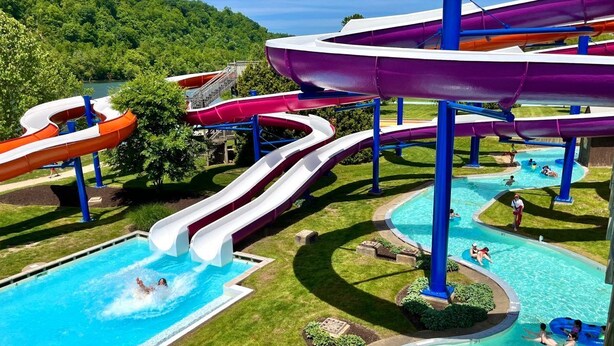 A water park with multiple slides and pools, surrounded by greenery.