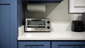 A kitchen with a built-in toaster oven on a white countertop, blue cabinets, and a roll of paper towels.