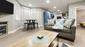A modern living room with a sofa, coffee table, and a TV mounted on the wall.