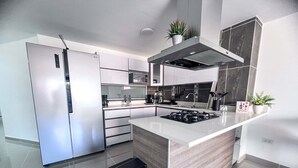Een moderne keuken met een vast kookeiland, roestvrijstalen apparatuur en een afvalbak.