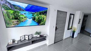 Een moderne hal met een groot flatscreen-televisie aan de wand, waarop een pittoresk landschap te zien is.