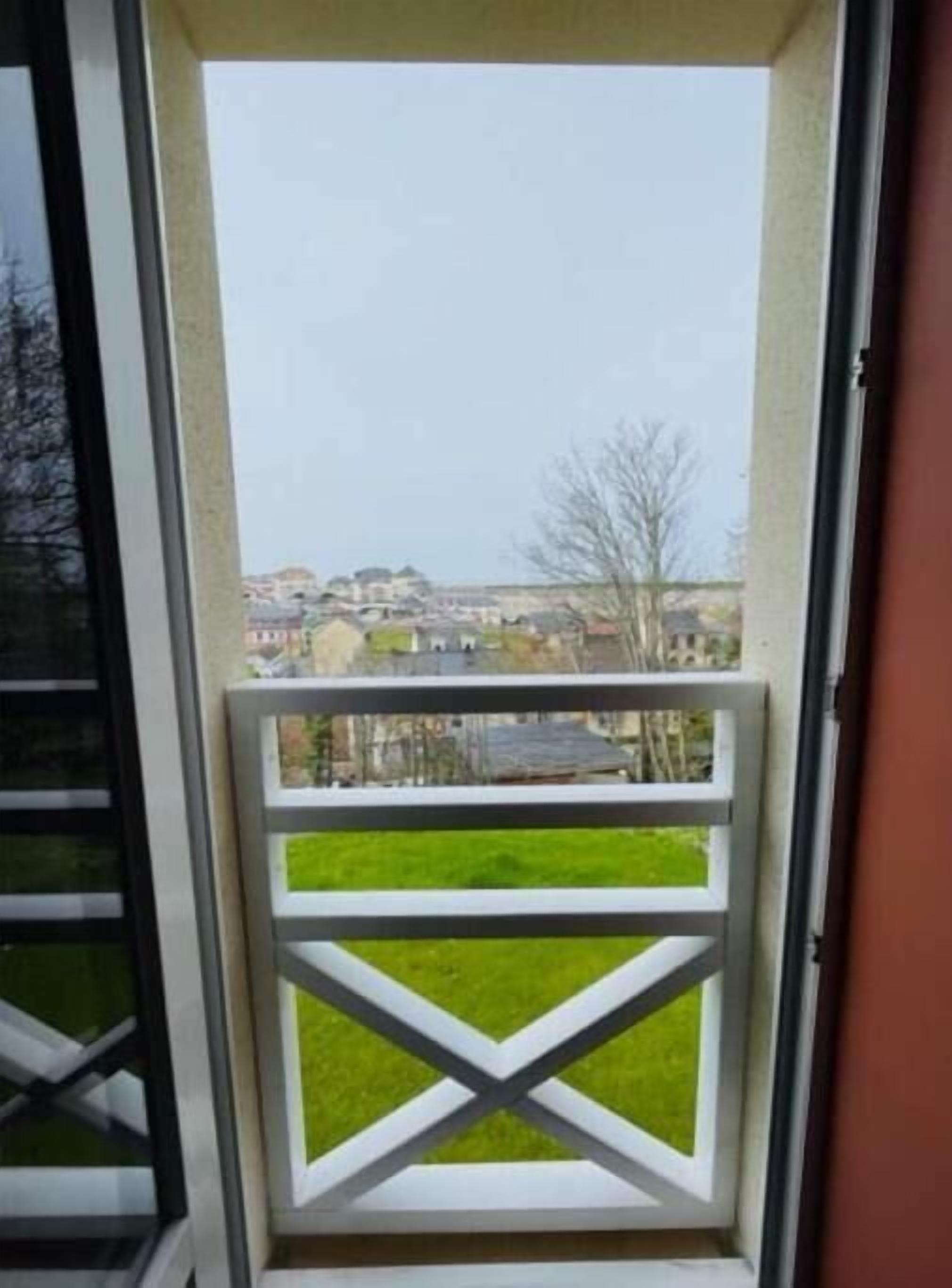 Un balcón con baranda blanca y vista a un barrio residencial.