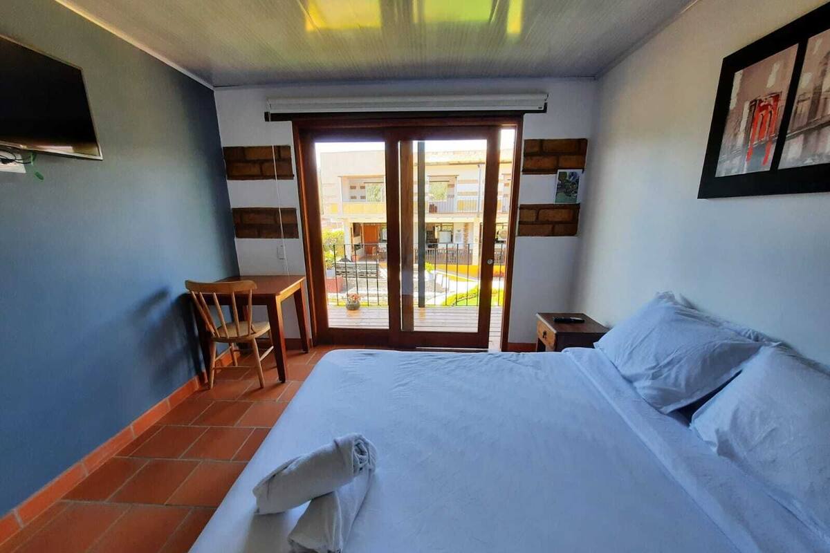 Une chambre d’hôtel avec un lit, une chaise, une petite table et une vue sur le balcon extérieur.