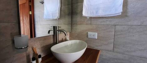 A bathroom with a large white sink, a mirror, and two white towels hanging on the wall.
