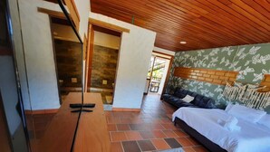 Un dormitorio con una cama, un sofá, techo de madera y pared de piedra.