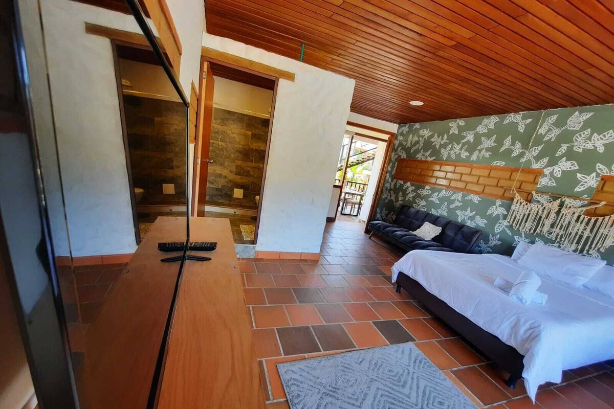 Une chambre à coucher avec un lit, un canapé, un plafond en bois et un mur en pierre.