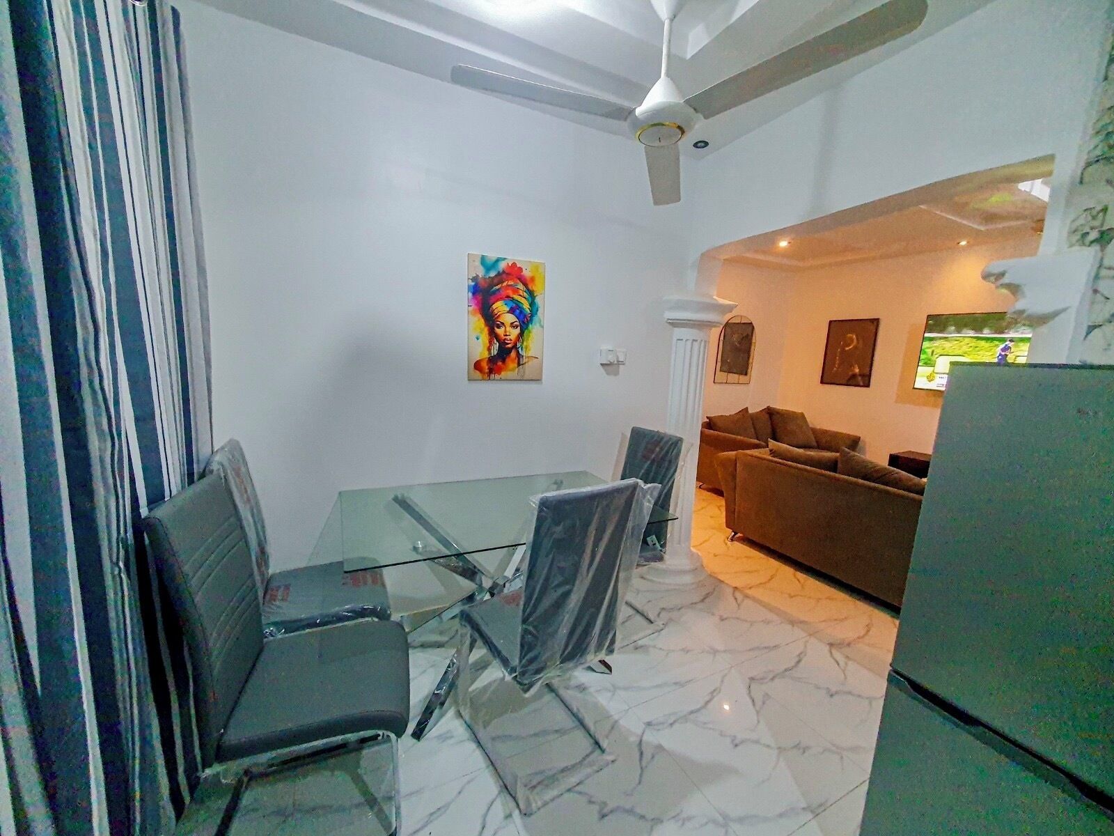 Una sala de estar moderna con una mesa de vidrio, sillas, un sofá y un televisor.