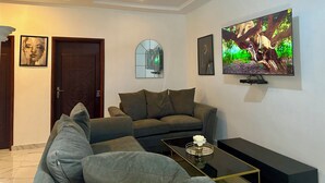 Een moderne woonkamer met een bank, een salontafel en een aan de muur bevestigde televisie.