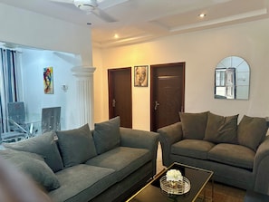 Ein Wohnzimmer mit zwei grauen Sofas, einem Couchtisch mit einer Vase und einem Spiegel an der Wand.