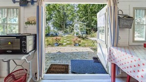 A cozy room with a kitchenette, a view of a garden, and a welcoming mat at the entrance.
