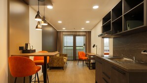 A modern kitchen with a built-in oven, a sink, and a dining area with orange chairs. - Trip Inn Hotel Frankfurt-Heusenstamm (Heusenstamm)