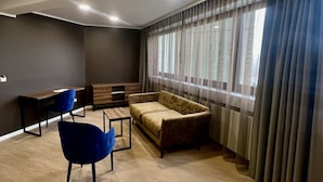 A modern living room with a sofa, two chairs, a coffee table, and a TV stand. - Trip Inn Hotel Frankfurt-Heusenstamm (Heusenstamm)