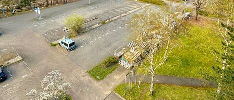 Luchtbeeld van een parkeerplaats met enkele auto's, omringd door bomen en groen.