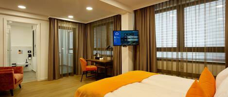 Una habitación de hotel con cama, escritorio, silla, televisor y baño.