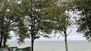 Vista de una playa con una cerca de madera y una estructura verde, probablemente un puesto de socorristas, con vista al océano.