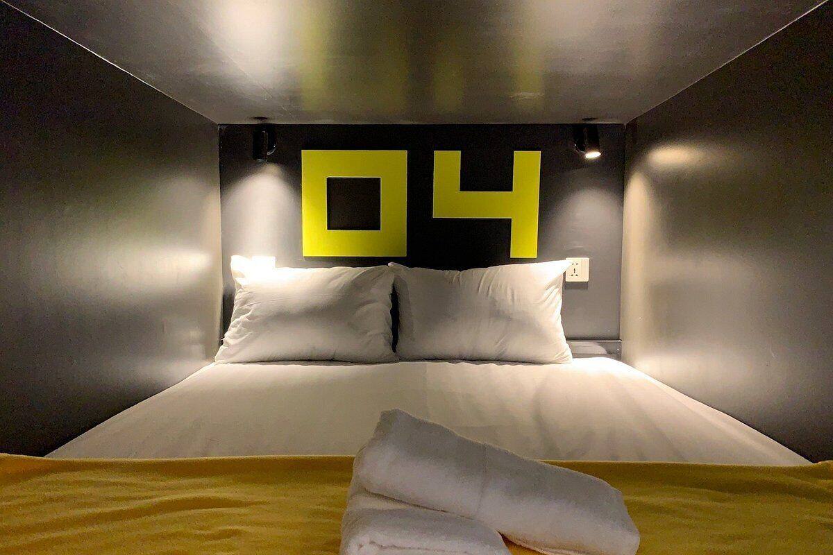 A hotel room with a bed, pillows, a towel, and a wall with the number 04.