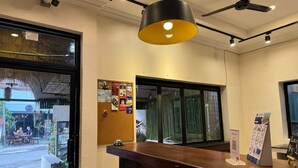 Un espace d’accueil avec un comptoir en bois, un ventilateur de plafond noir et une grande fenêtre avec des rideaux.