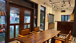 Un espace repas avec une table et des chaises en bois, de grandes fenêtres et une vue sur l’extérieur.