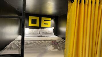 A bunk bed room with a number '06' on the wall, white bedding, and a yellow curtain.