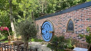 A brick building with a large blue door and a smaller window, surrounded by greenery and a stone pathway. - The Hobbit du Domaine de la Calotine (Dives-sur-Mer)