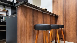A modern kitchen with a wooden island, black bar stools, and pendant lighting.