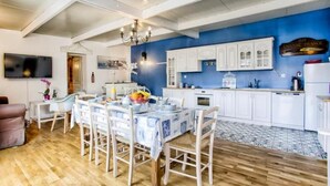 Un coin repas avec une table dressée pour quatre personnes, une cuisine avec des meubles blancs et un mur d’accent bleu.