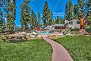 Un chalet doté d’une piscine, d’une table de pique-nique et d’un sentier pédestre, le tout entouré d’arbres.