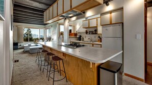 A modern kitchen with a large island, bar stools, and a built-in stove. - Entire Townhouse in Lake Village with Stunning Lake View! (Glenbrook)