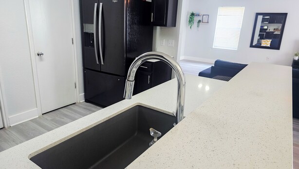 A modern kitchen with a stainless steel sink, black appliances, and a white speckled countertop. - Experience Austin from this impressive 2,000 sq. ft. Two-Story Home. Designed for groups and professionals, this property offers a versatile layout with a charming backyard and functional dining area. (Austin)