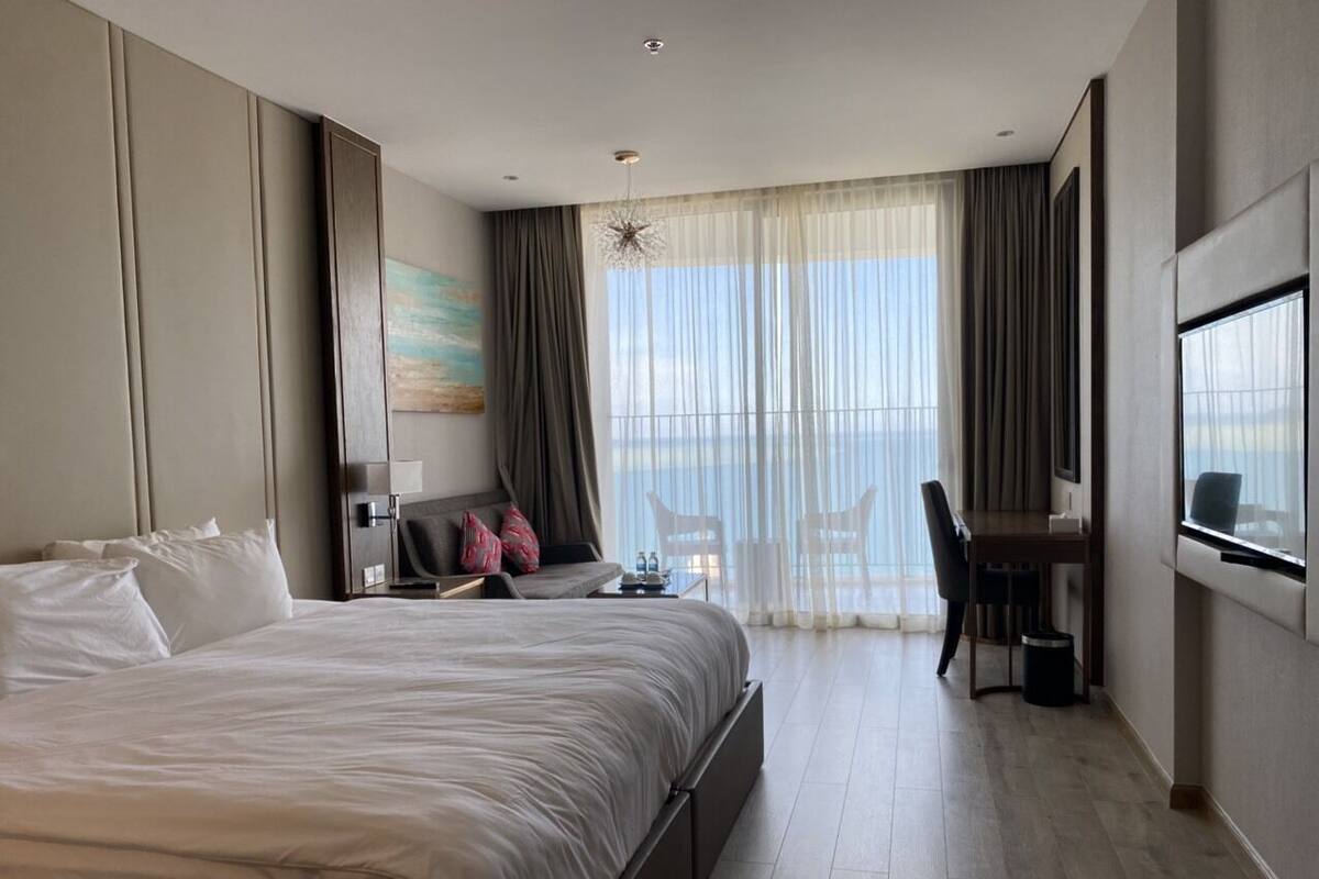 Habitación de hotel moderna con una cama grande, un escritorio y vistas al mar.